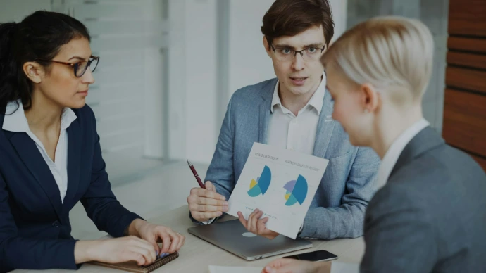 Drie professionals die grafieken bespreken in een vergadering